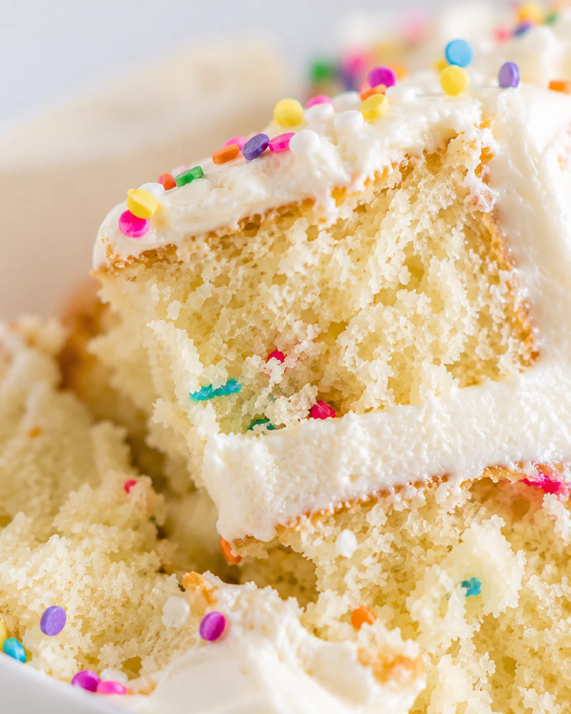 Close-up of a moist vanilla cake with colorful sprinkles and creamy frosting