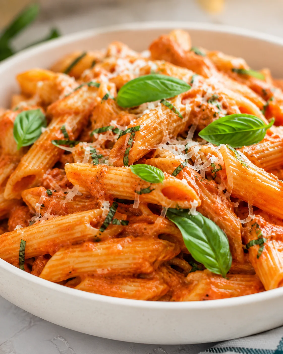 Delicious homemade penne pasta in rich red tomato sauce garnished with basil and Parmesan
