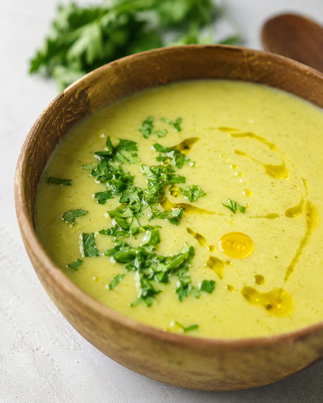 A bowl of creamy zucchini soup topped with fresh herbs and a drizzle of oil.