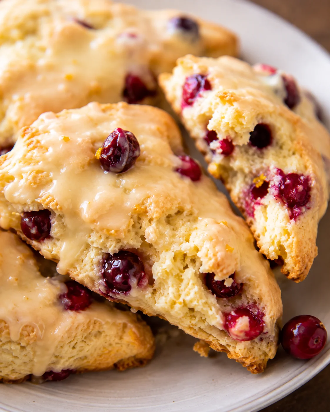 Plated cranberry orange scones with glaze and visible cranberries