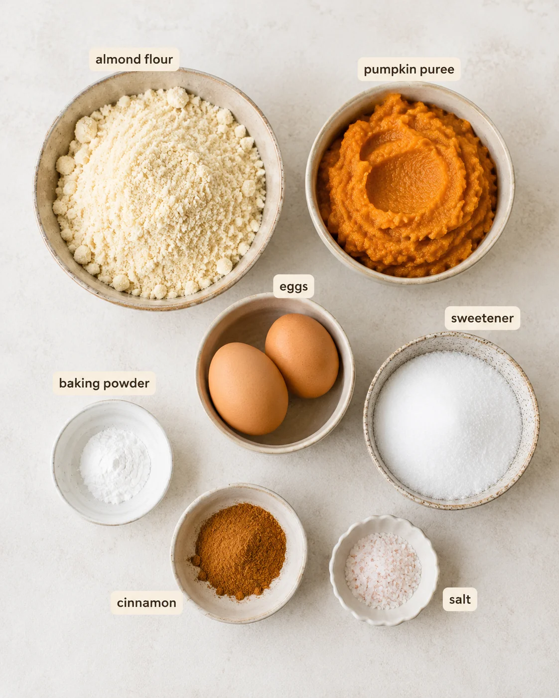 Top-down layout of ingredients for keto pumpkin bread including almond flour, pumpkin puree, eggs, sweetener, and spices