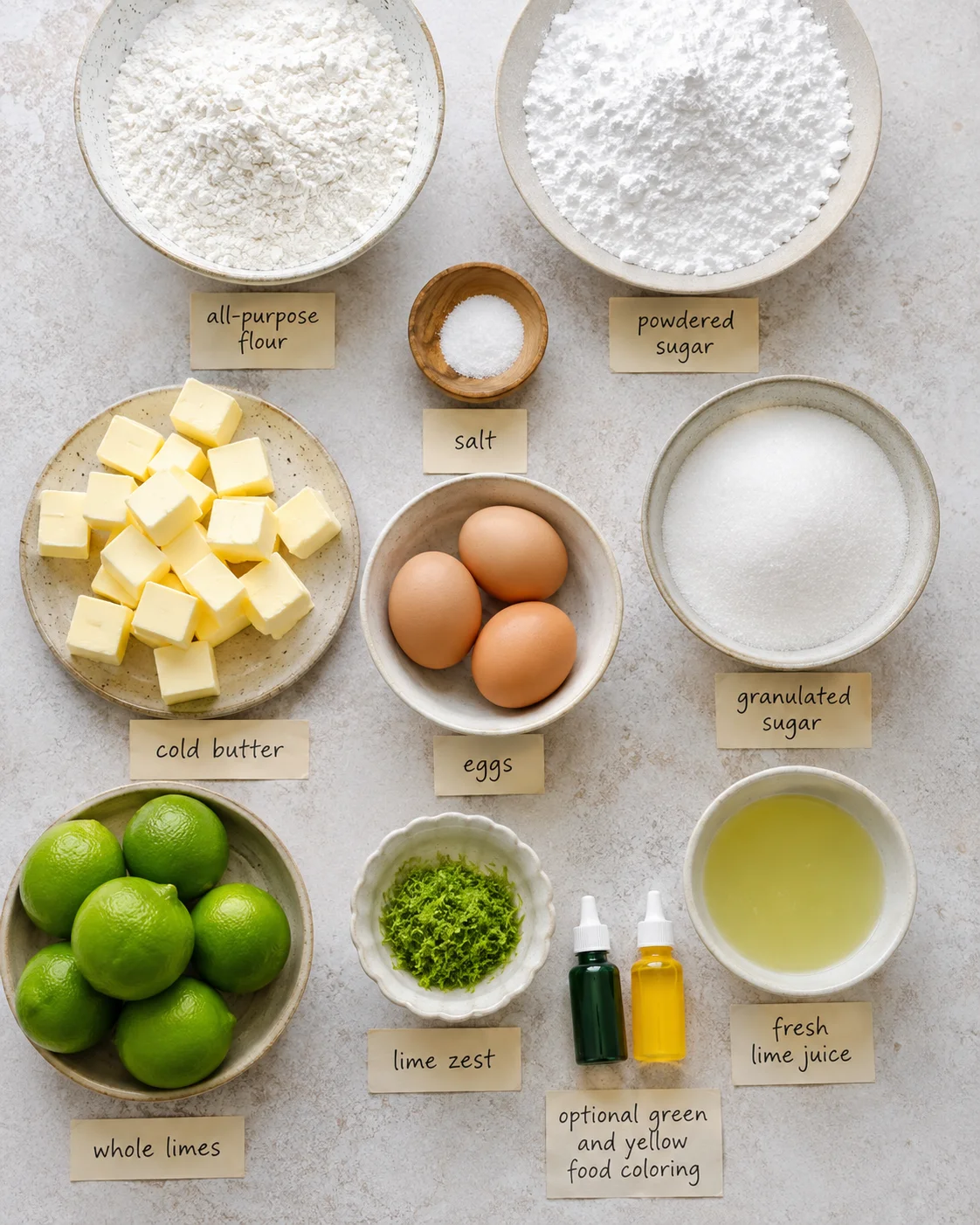 Top-down arrangement of ingredients for lime bars including flour, powdered sugar, butter, eggs, limes, lime zest, sugar, and lime juice