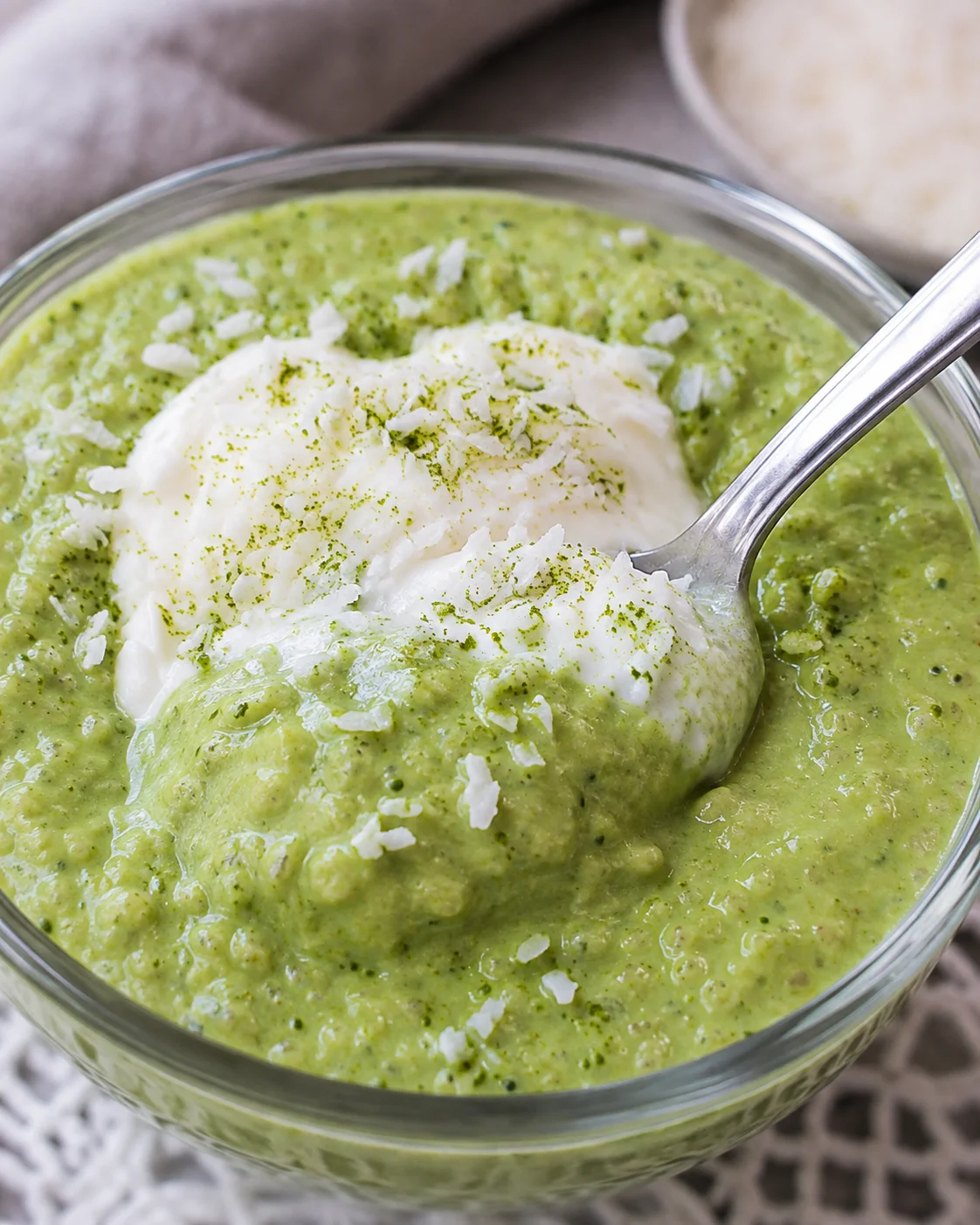 Creamy Matcha Chia Pudding A glass bowl of vibrant green matcha chia pudding topped with coconut flakes and a spoon.