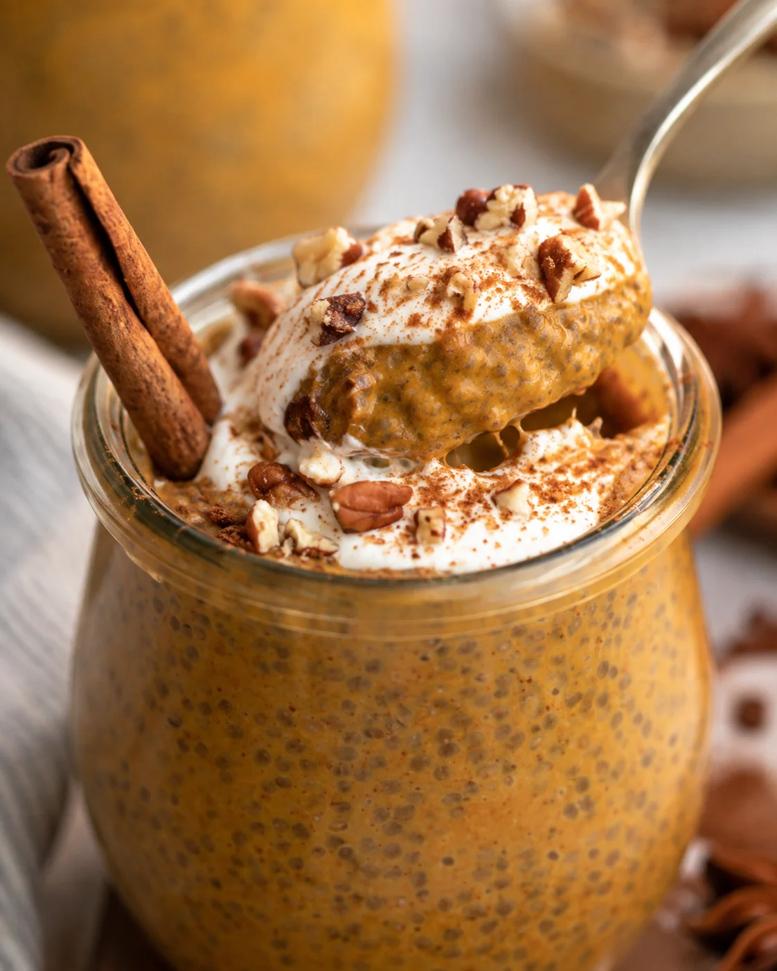Creamy pumpkin chia pudding topped with whipped cream and chopped nuts.