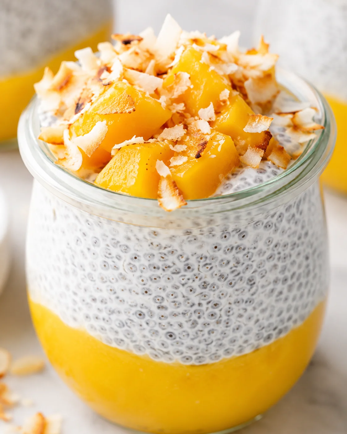 Delicious mango chia pudding topped with toasted coconut and fresh mango chunks.