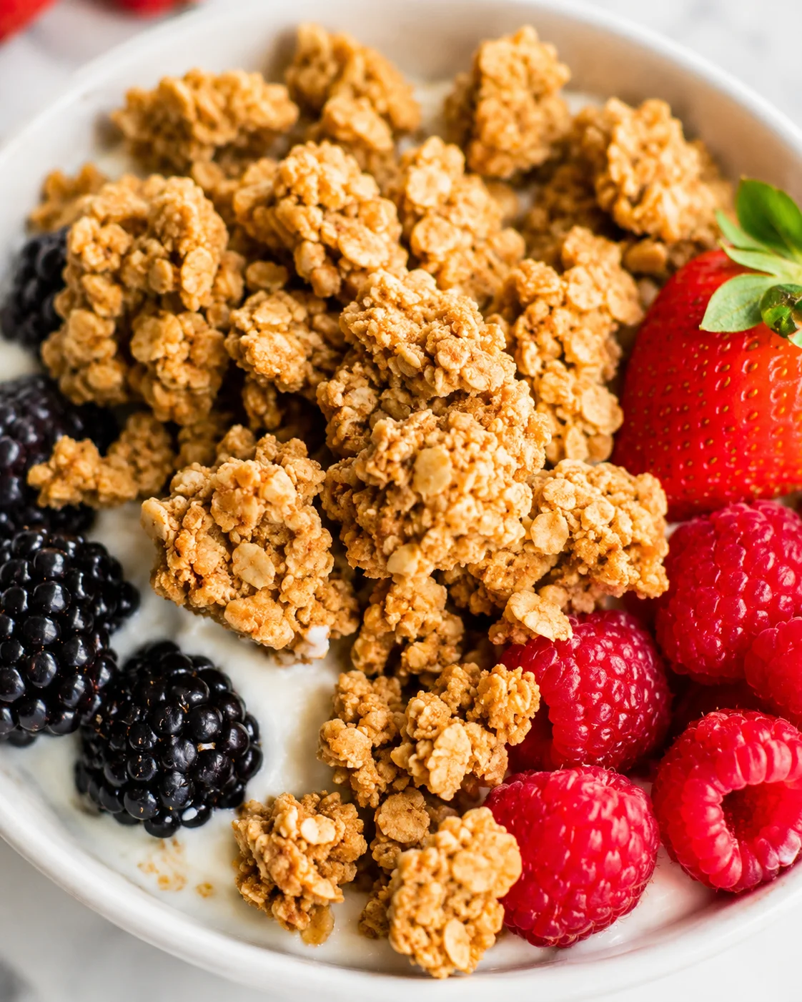Crunchy homemade peanut butter granola with fresh berries on a white bowl