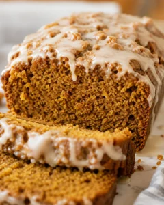 Close side view of sliced pumpkin banana bread topped with maple glaze
