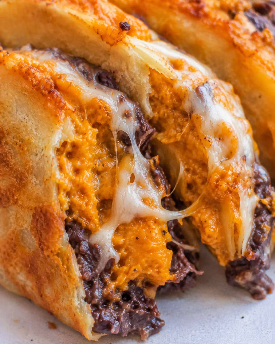 Close-up of a pumpkin and black bean taco interior with gooey cheese stretching