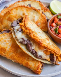 Side view of crispy pumpkin and black bean tacos showing melted cheese and browned tortilla edges