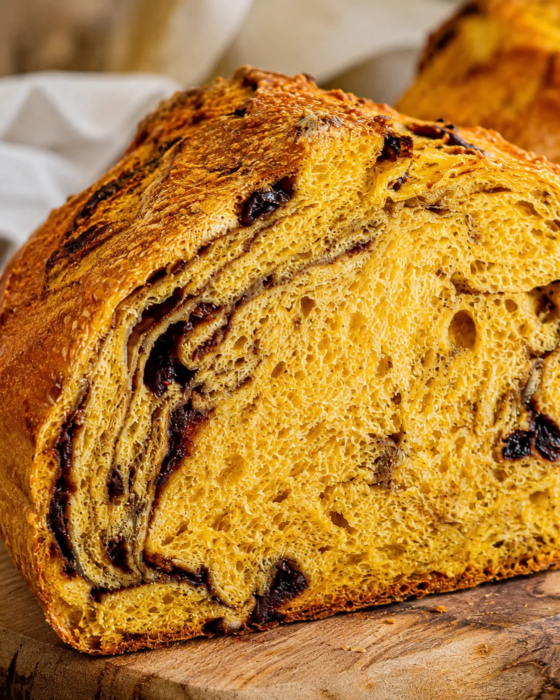 Close-up side view of a sliced pumpkin sourdough bread showing golden crumb and dark swirls