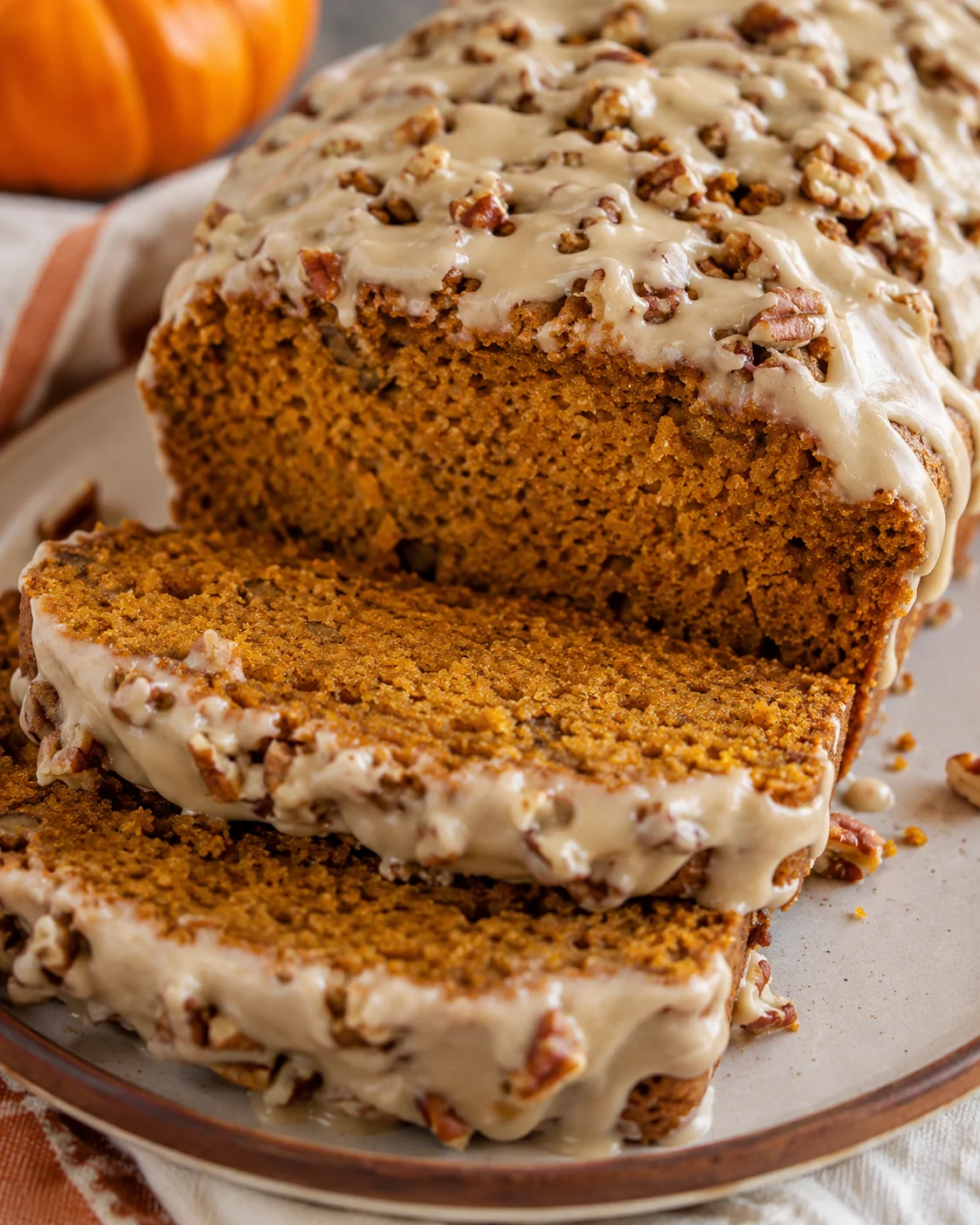 Sliced maple pumpkin bread with pecan topping and maple glaze on a plate